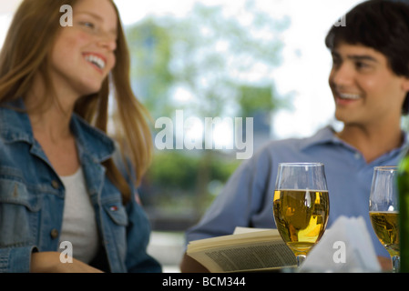 Friends laughing in outdoor cafe, glasses of beer in foreground Stock Photo