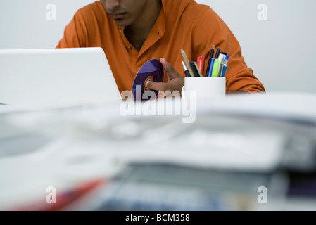 Man working at messy desk, holding CD, cropped view Stock Photo