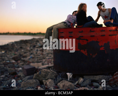 Three young friends sitting on top of dumpster Stock Photo