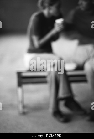 Couple sitting on bench, drinking coffee, defocused Stock Photo