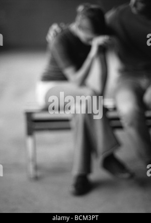Couple sitting on bench, woman crying, defocused Stock Photo
