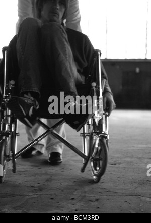 Man in wheelchair being pushed by orderly Stock Photo