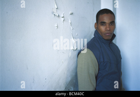 Young man standing in corner, looking at camera Stock Photo