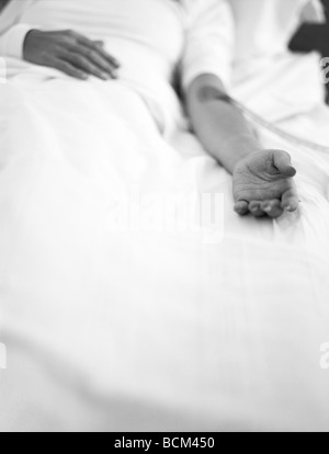 Patient lying in hospital bed with IV drip Stock Photo