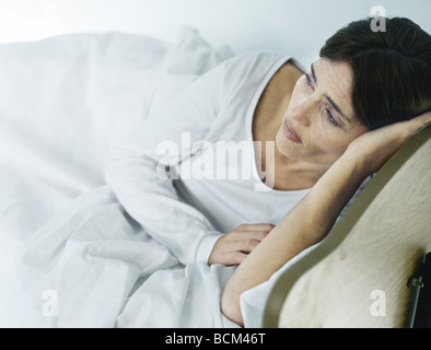 Woman lying in bed, looking away with sad expression