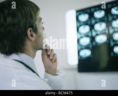 Doctor looking at MRI scans, hand under chin Stock Photo