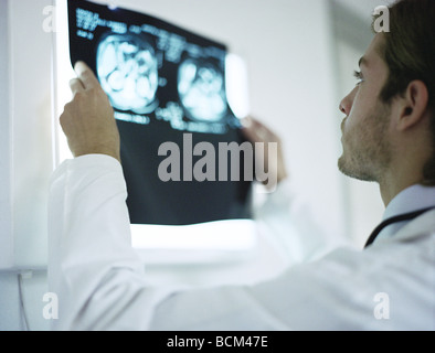 Doctor holding up and examining MRI images, rear view Stock Photo