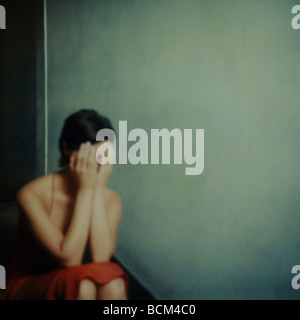 Young woman covering face, sitting on stairs Stock Photo