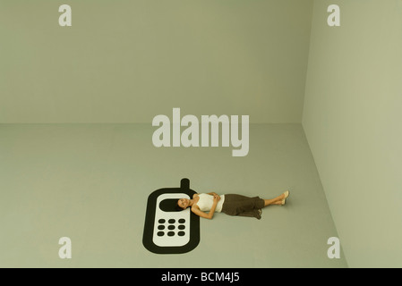 Woman lying on back on large cell phone, high angle view Stock Photo
