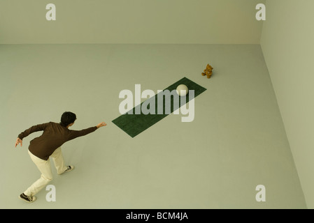 Man throwing bowling ball at teddy bear, high angle view Stock Photo