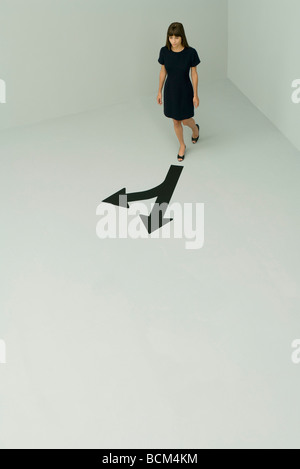 Woman walking, arrows pointing different directions, high angle view Stock Photo