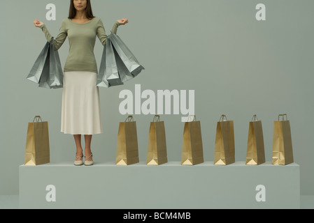 Woman holding several shopping bags, more bags lined up beside her, cropped view Stock Photo