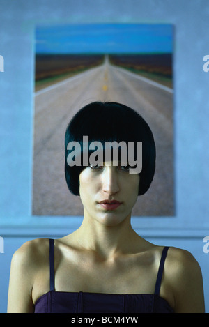 Woman staring at camera, portrait, painting of highway in background Stock Photo