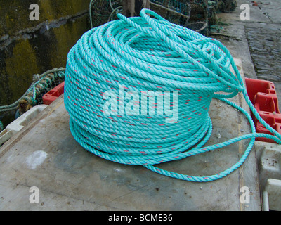 A coil of new blue green rope on the quayside Stock Photo