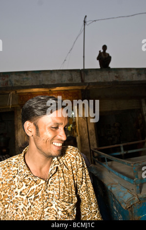 Man in leopard print shirt on street in dhaka bangladesh with sihouette of boy on roof behind Stock Photo