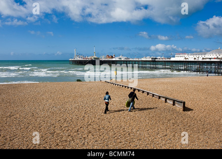 Two people walking on the shingle beach near the pier in Brighton in Sussex.  Photo by Gordon Scammell Stock Photo