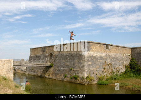 Stock photo of boys leaping from the city walls on the ile d oleron in France and landing in the sea Good fun or what Stock Photo