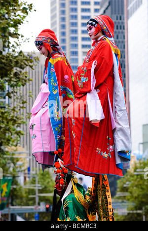 Two young Chinese women in colourful traditional costume, being carried during a Chinese New Year parade. Stock Photo