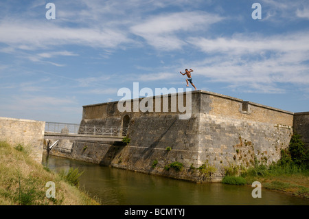 Stock photo of boys leaping from the city walls on the ile d oleron in France and landing in the sea Good fun or what Stock Photo