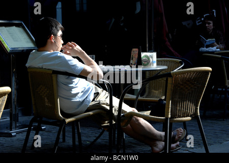 Young man wearing earphone resting in the open air café, Shanghai, China Stock Photo