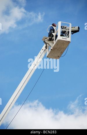 A television cameraman on an elevated camera crane at an auto racing event. Stock Photo