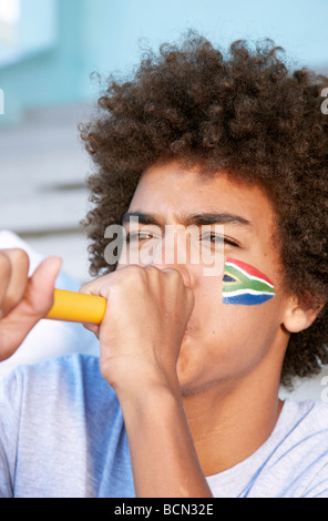 Sports fan with South African flag painted on his cheek blowing a vuvuzela. Cape Town, Western Cape Province, South Africa Stock Photo