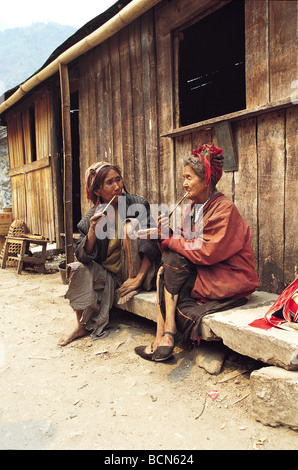 Two Lisu ethnic minority women smoking pipes before their home, Ailaoshan Mountian, Yunnan Province, China Stock Photo