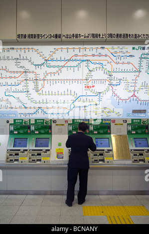 A commuter retrieving ticket at an automatic vending machine in a subway entrance gate. Tokyo Japan Stock Photo