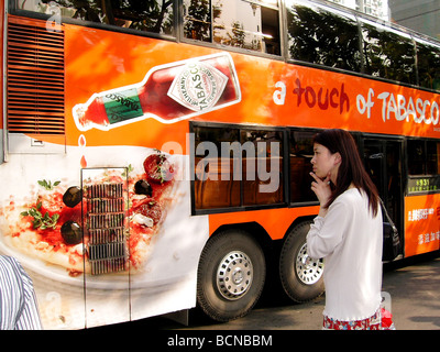 Tourist walking pass bus with large advertisement, Shanghai, China Stock Photo