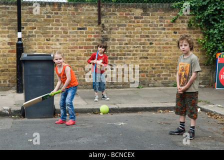 Children playing cricket in the street boy and girls. Brunswick Street Walthamstow London E17 Using the dustbin at the wicket. 2009 2000s HOMER SYKES Stock Photo