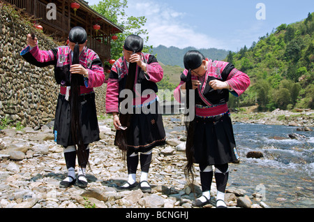 Three Yao Long Hair women combing hair beside river Huangluo Village Guangxi China Stock Photo