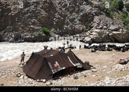 A black tent and goats beside the fast flowing Panjshir river mark a nomadic Kuchi family's encampment Stock Photo