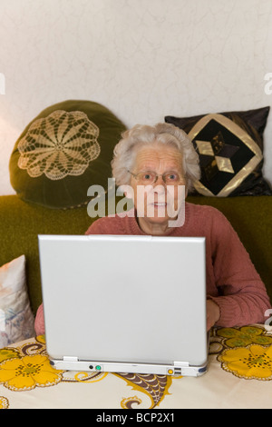 Frau in ihren Siebzigern sitzt im Wohnzimmer am Laptop