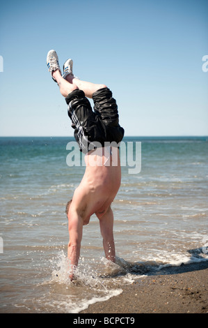 Man doing handstand on Aberystwyth beach summer afternoon Stock Photo