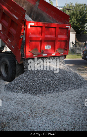 A dump truck unloading unloads gravel on a parking lot in a city street close up closeup USA US nobody vertical hi-res Stock Photo