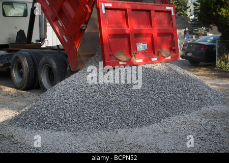 A dump truck unloading unloads gravel on a parking lot in a city street close up closeup USA US nobody horizontal hi-res Stock Photo