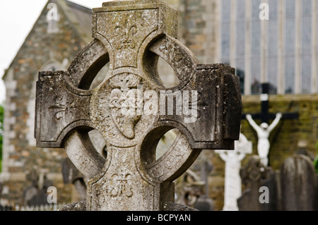 Granite celtic cross with sacred heart carved in centre, in a church graveyard. Stock Photo