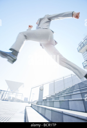 Businessman jumping down stairs Stock Photo