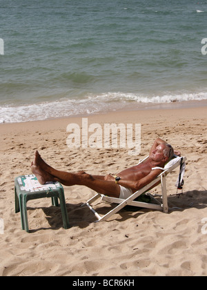 Male relaxing on the Beach Pattaya Beach in Thailand with beach vendors