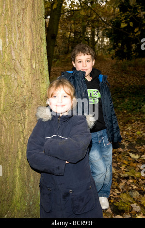 Young brother and sister boy and girl with arms folded in autumn woods. FULLY MODEL RELEASED Stock Photo