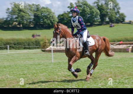 Teenage girl riding in cross-country event on brown pony. Stock Photo