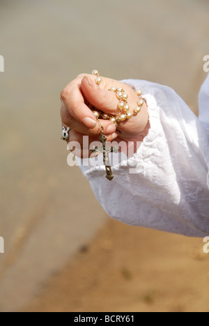 woman holding rosary by lake in her hand Stock Photo