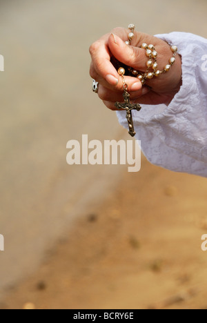 woman holding rosary by lake in her hand Stock Photo