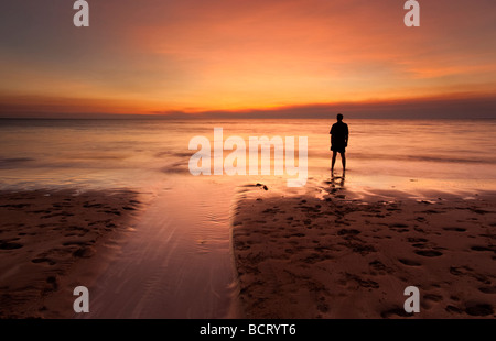 Silhouette of a man standing on the seashore watching the sunset. Dripstone Beach, Darwin, Northern Territory, Australia