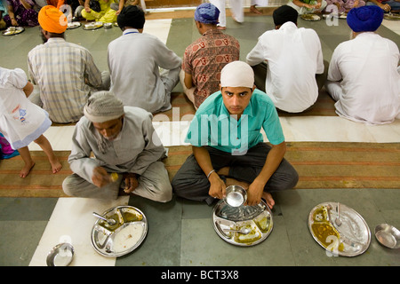 Sikh men eating a free meal served in the Community kitchen at the The Golden Temple (Sri Harmandir Sahib) Amritsar. India. Stock Photo