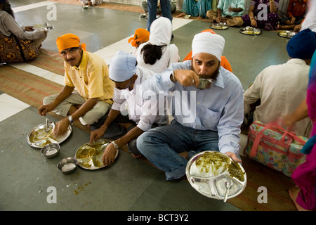 Sikh men eating a free meal served in the Community kitchen at the The Golden Temple (Sri Harmandir Sahib) Amritsar. India. Stock Photo