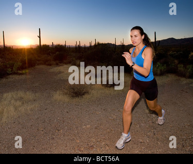 Fit and healthy young woman running in the desert at sunset Stock Photo