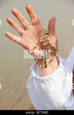 woman holding rosary by lake in her hand Stock Photo