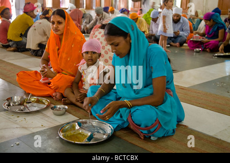 Sikh women eating a free meal served in the Community kitchen at the The Golden Temple (Sri Harmandir Sahib) Amritsar. India. Stock Photo