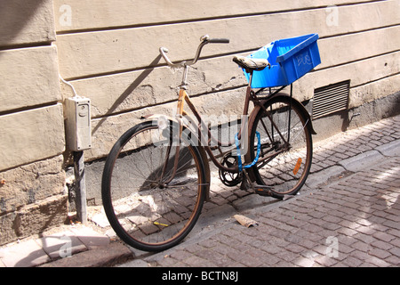 A sit up and beg bike leaning against a wall in Stockholm, with a blue plastic box on the back. Stock Photo